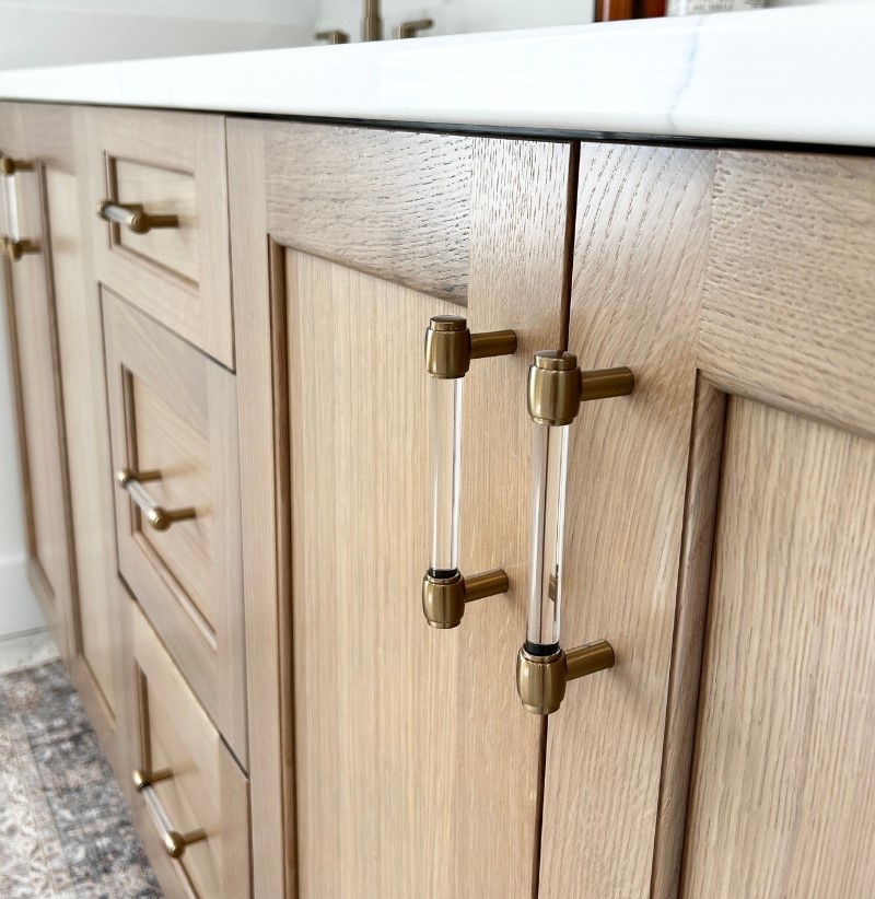 closeup shot of white oak vanity with brass and clear acrylic handle hardware