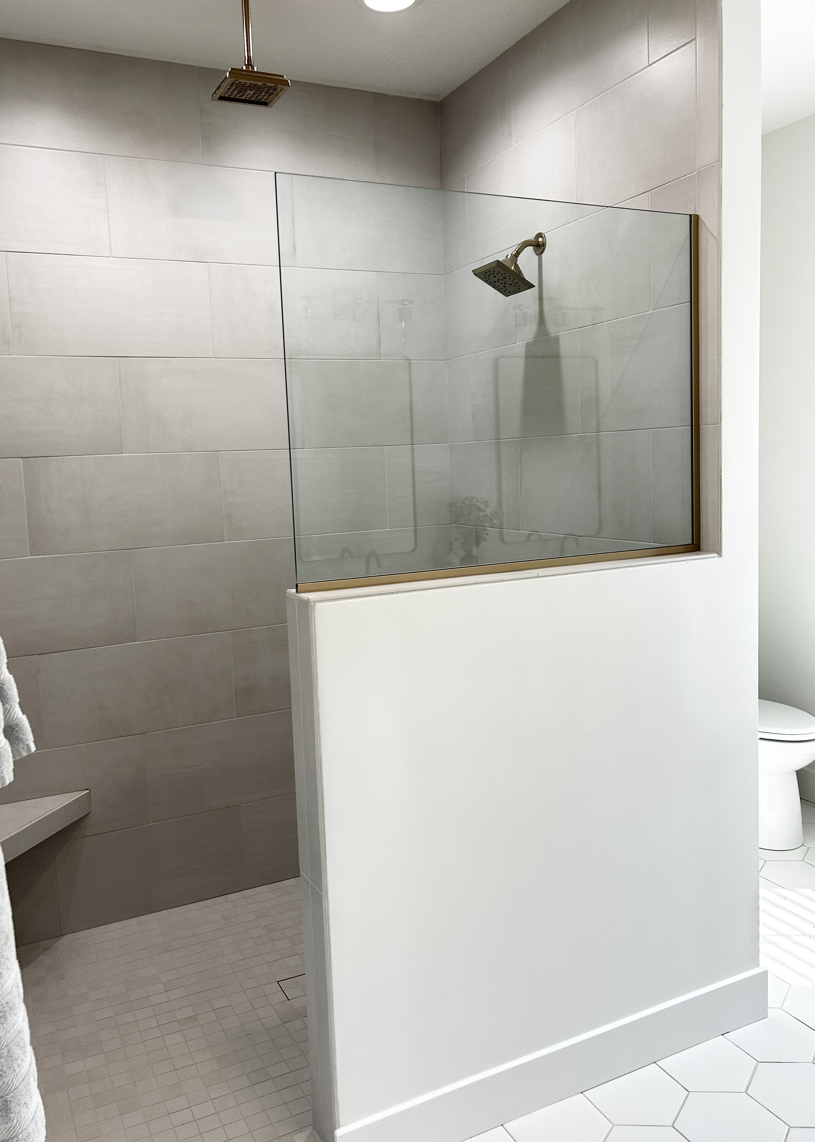 tiled shower with half wall and shower glass