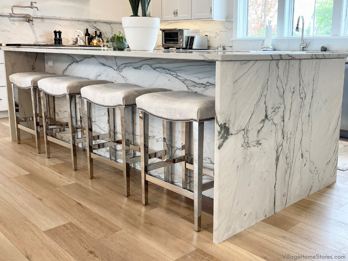 kitchen island wrapped with florida wave quartzite natural stone on ends and back with counter chrome bar stools under seating overhang