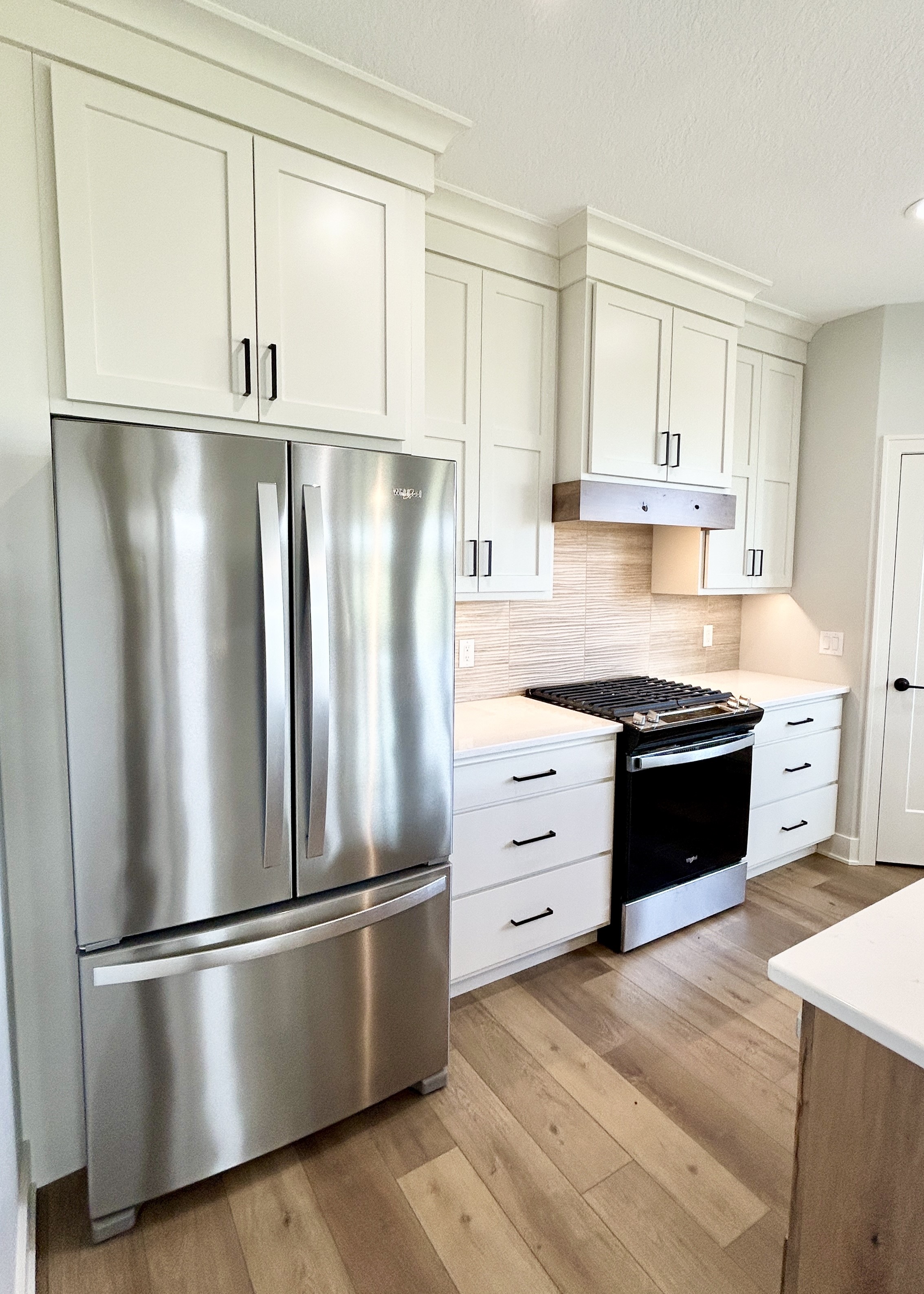 Shoji White painted kitchen with stainless steel Whirlpool appliances including a French Door fridge at the foreground