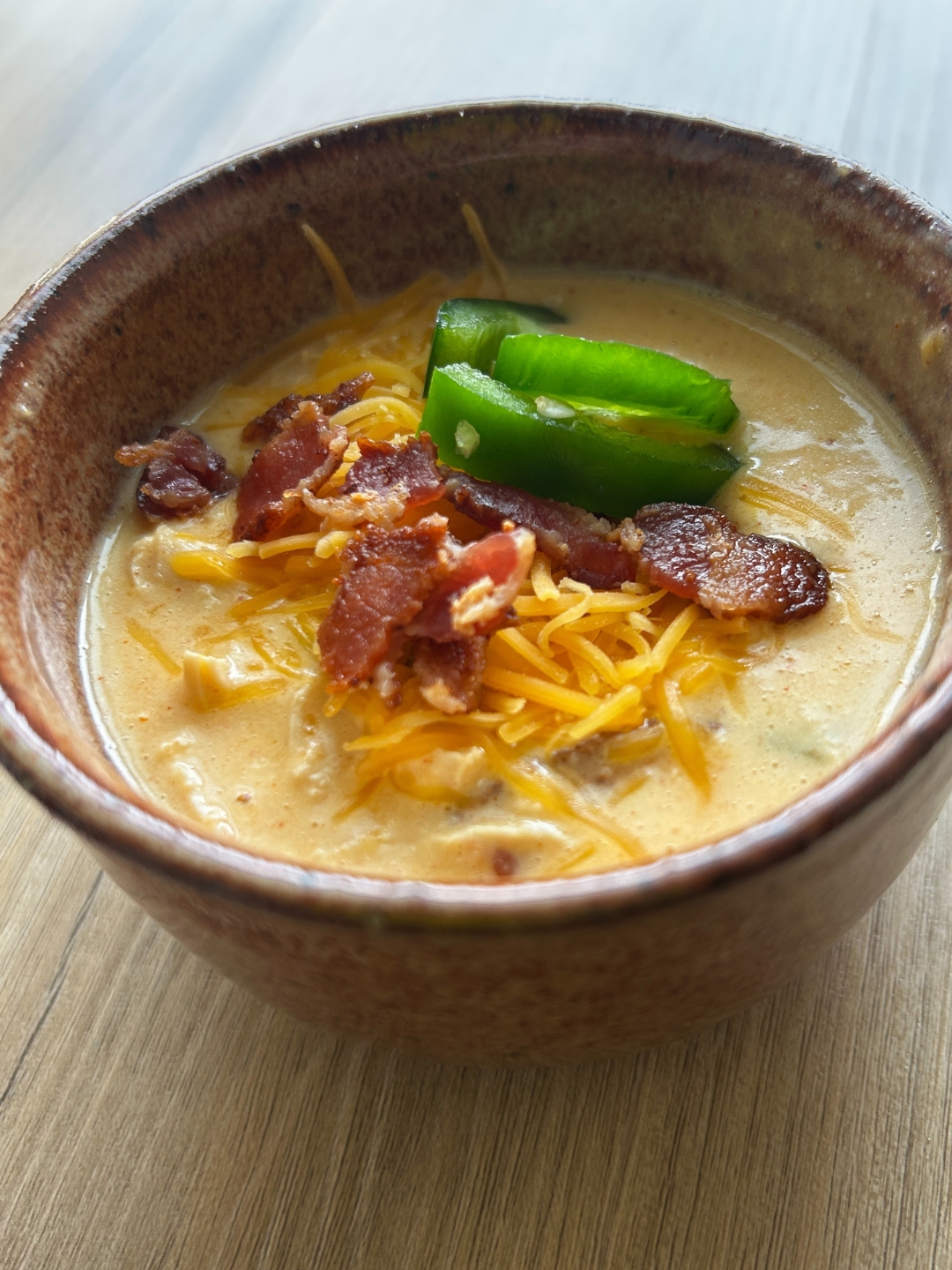 bowl of cheesy chicken jalapeno soup with bacon and cheese and jalapeno slices as garnish