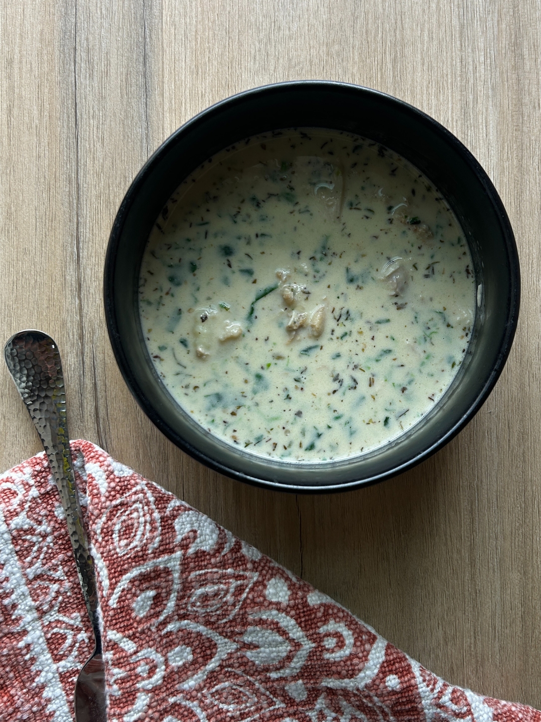 bowl of creamy garlic gnocchi soup with cloth napkin and spoon on table