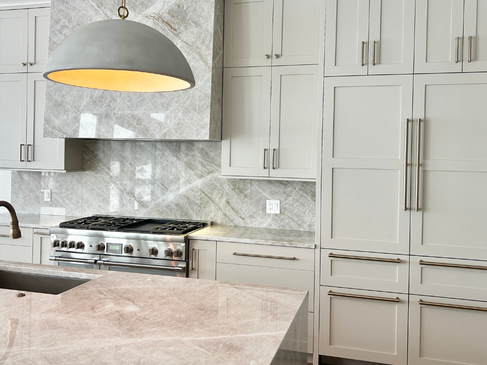 accessible beige kitchen cabinets with taj mahal quartzite countertops and custom range hood