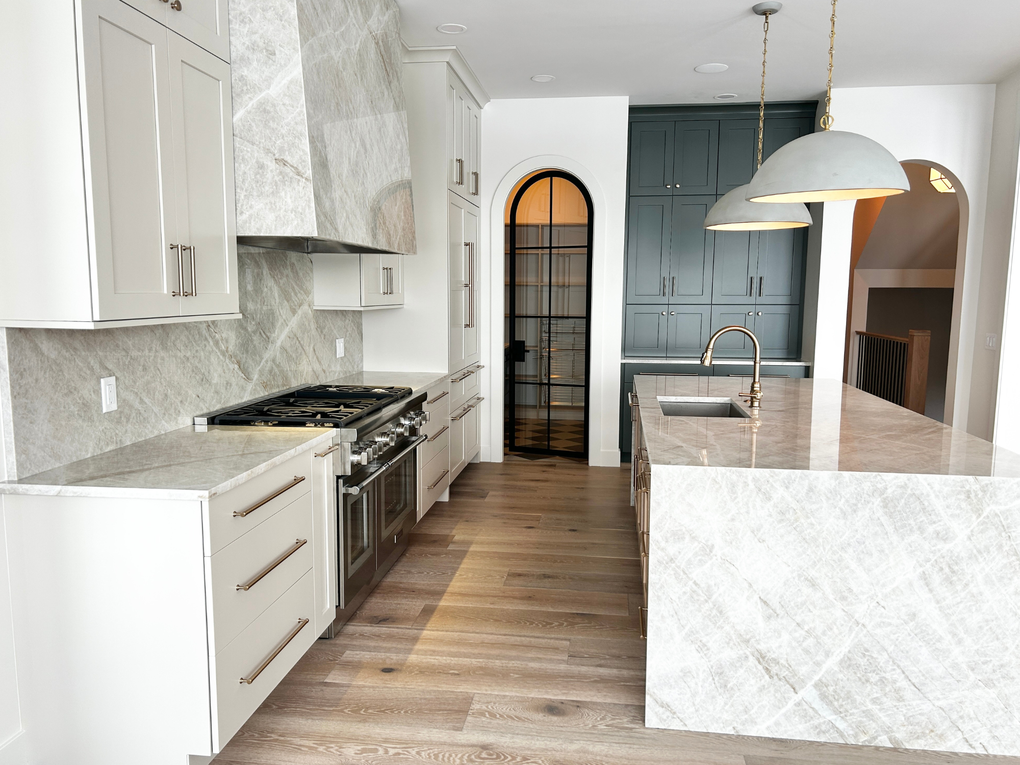 kitchen with taj mahal quartzite countertops, backsplash and custom range hood installed in a village home stores kitchen in the quad cities