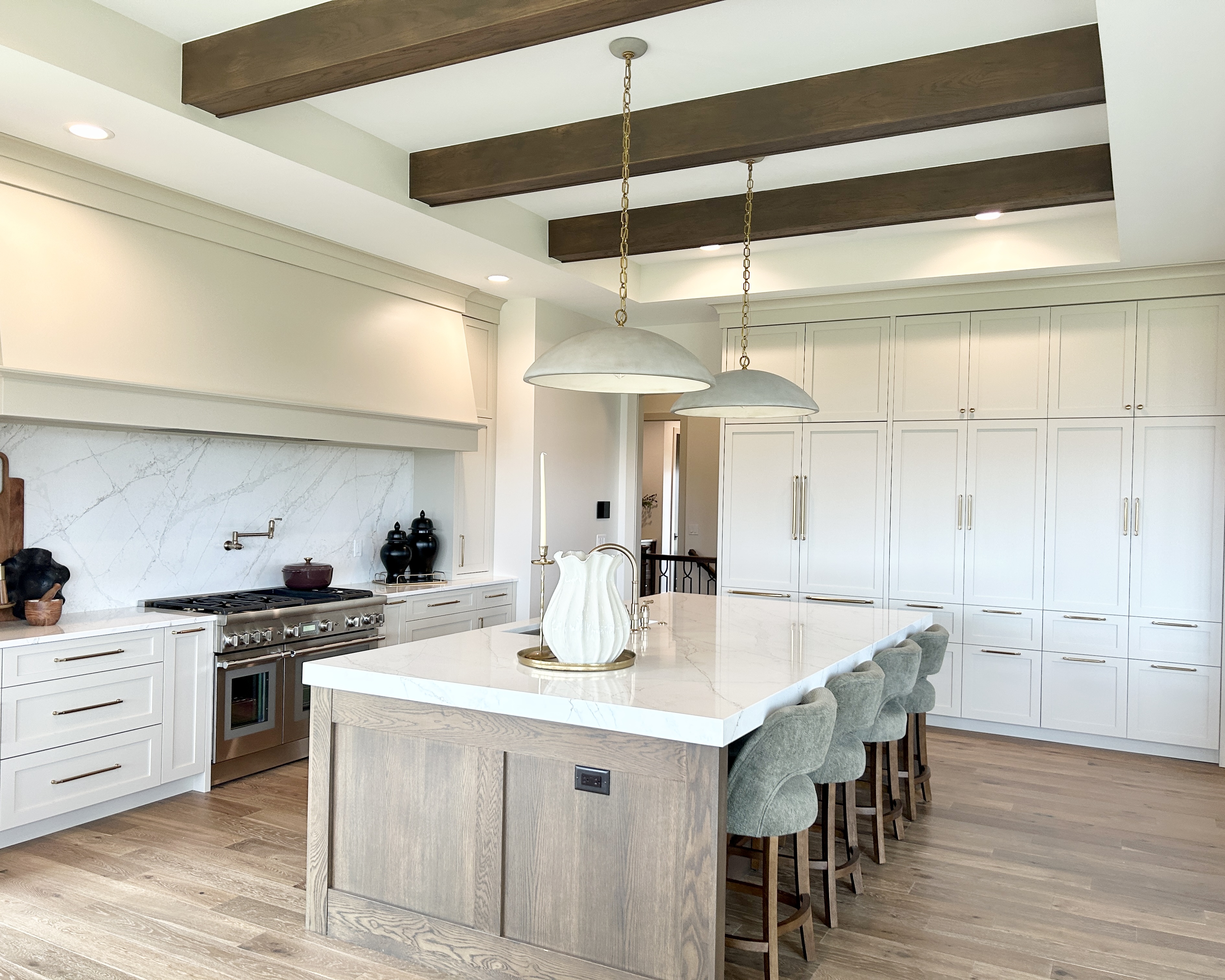 village home stores kitchen design with large island and thick quartz top with two cement look pendant lights and beamed ceiling in a model home built by windmiller design build