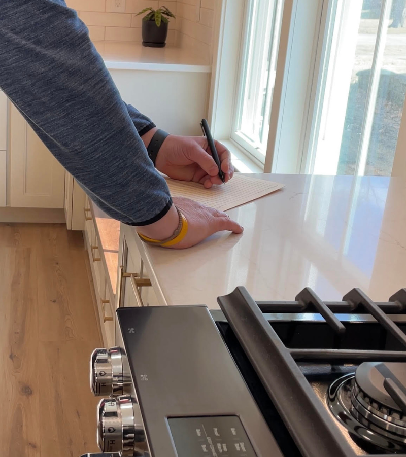 closeup of man in blue sleeves making notes on file folder in kitchen