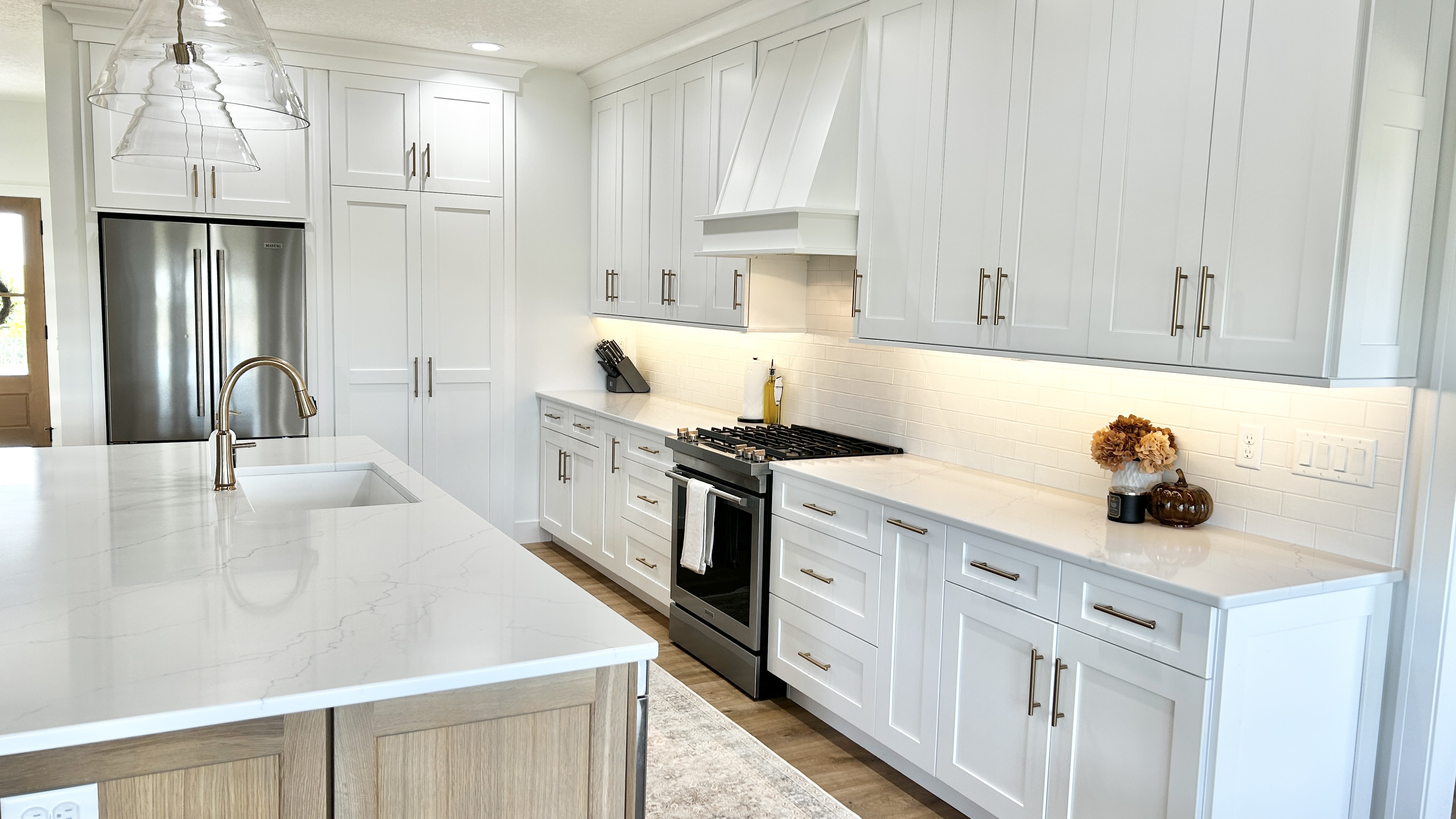 white cabinet kitchen design by village home stores with large island and clear glass pendant lights