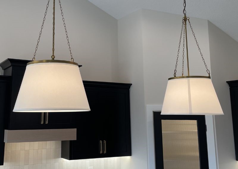 aged brass and linen shade pendant lights in kitchen