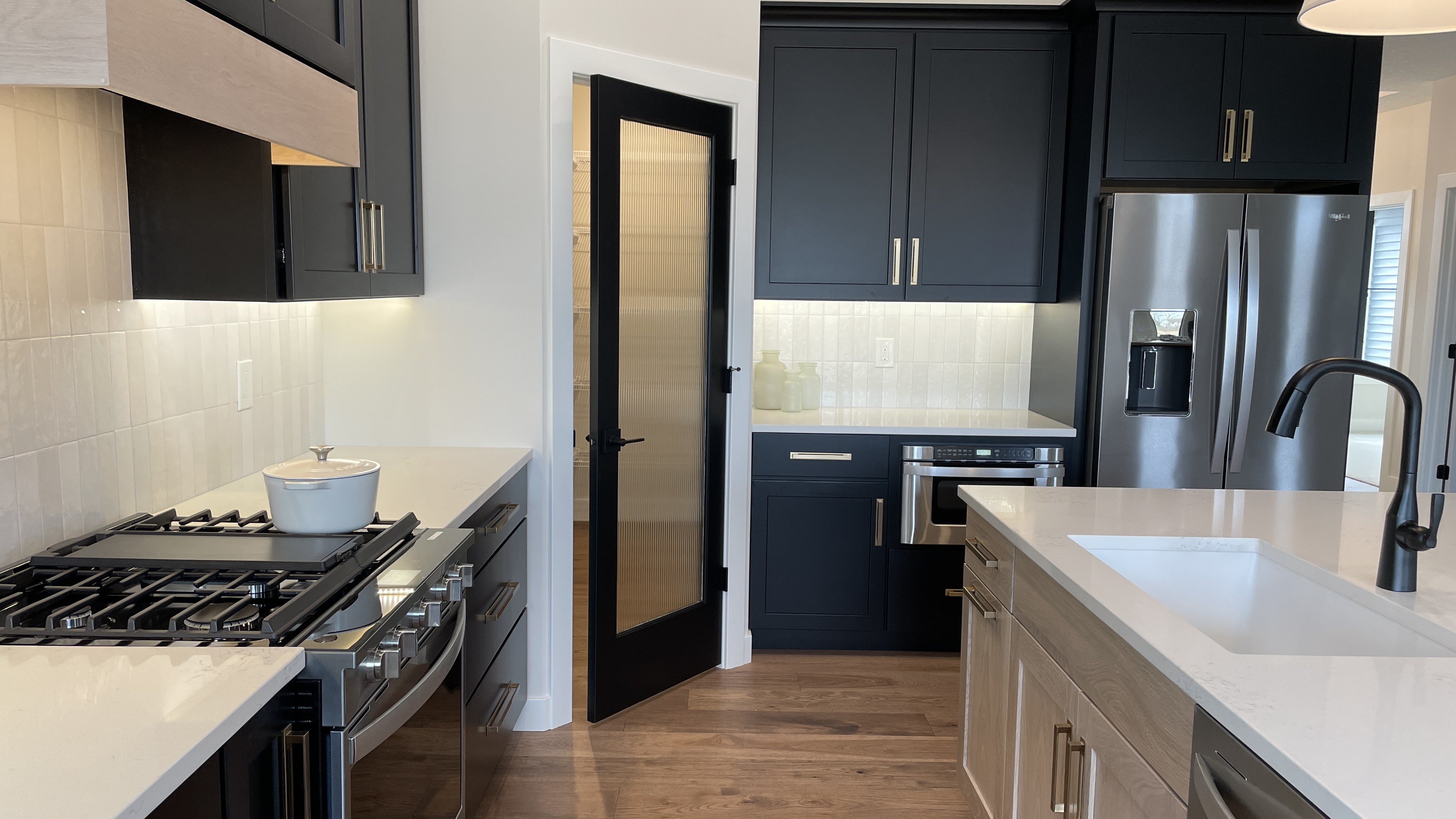 corner of kitchen design with reeded glass pantry door and black cabinets