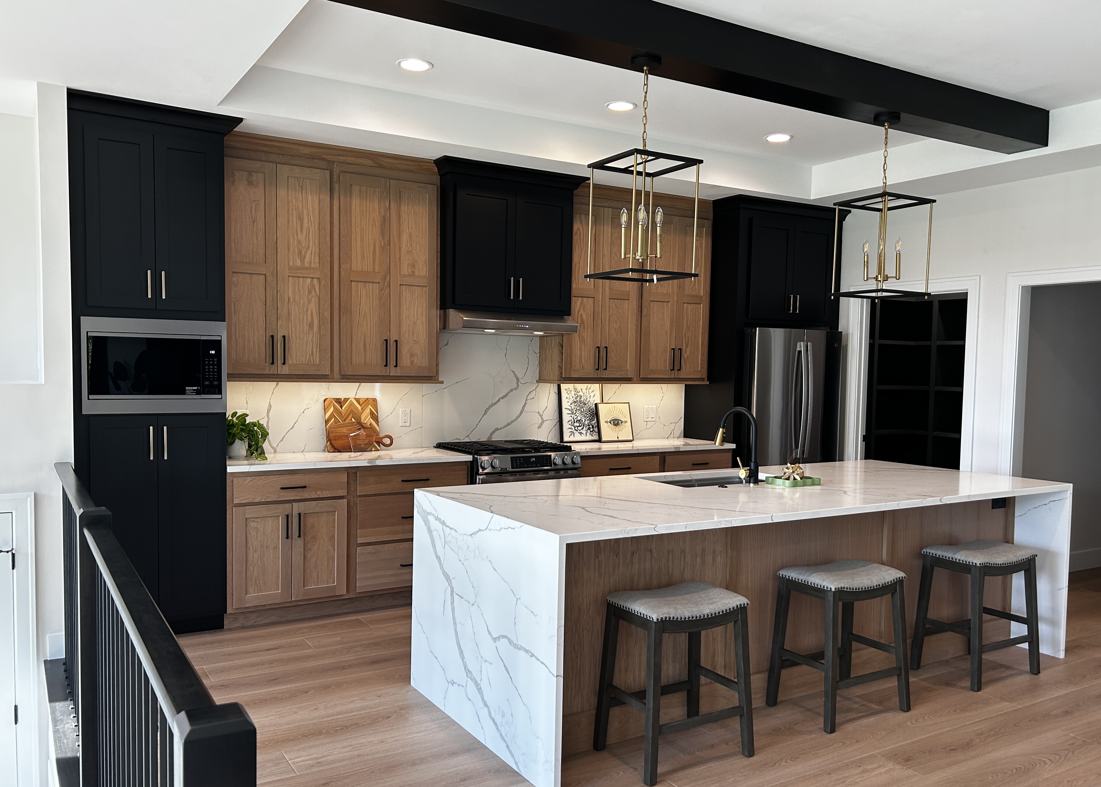 builtqc kitchen design from Village Home Stores with main wall of cabinetry and large island with waterfall counters