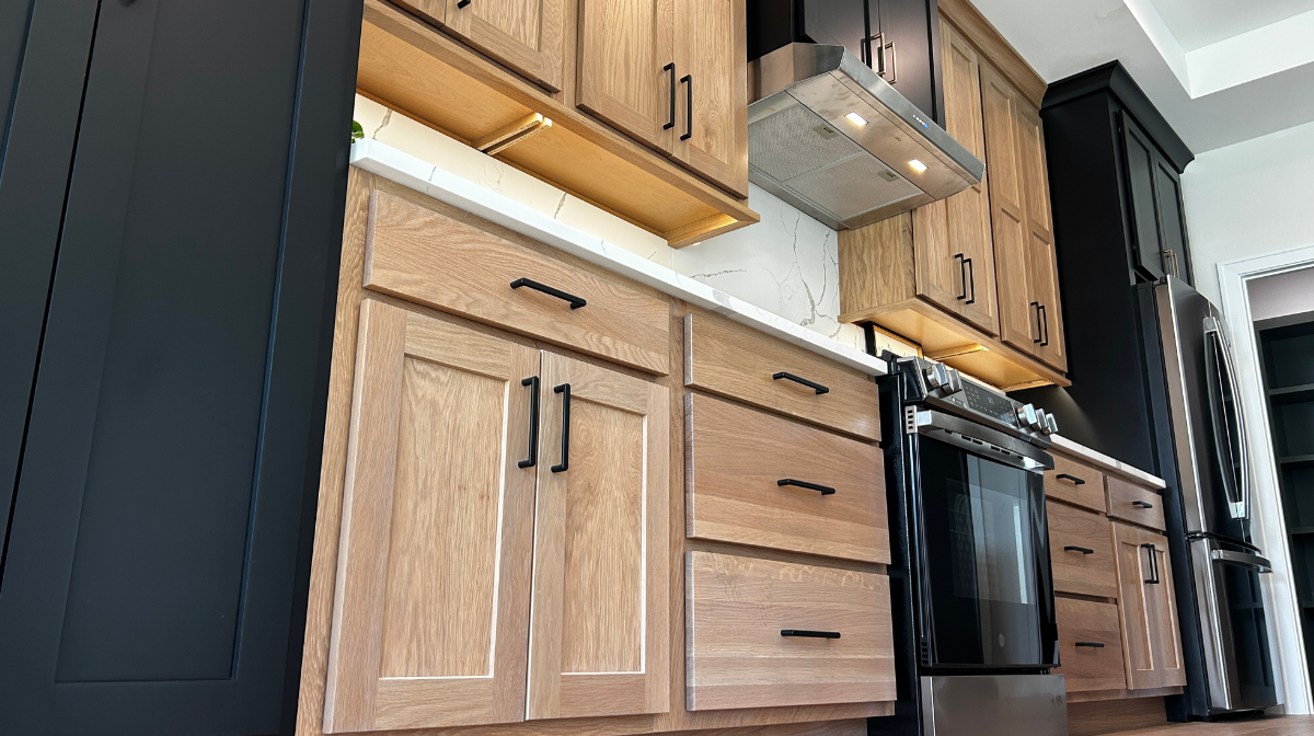 view of kitchen cabinets from floor with black painted cabinets and white oak wheat-stained light wood cabinets