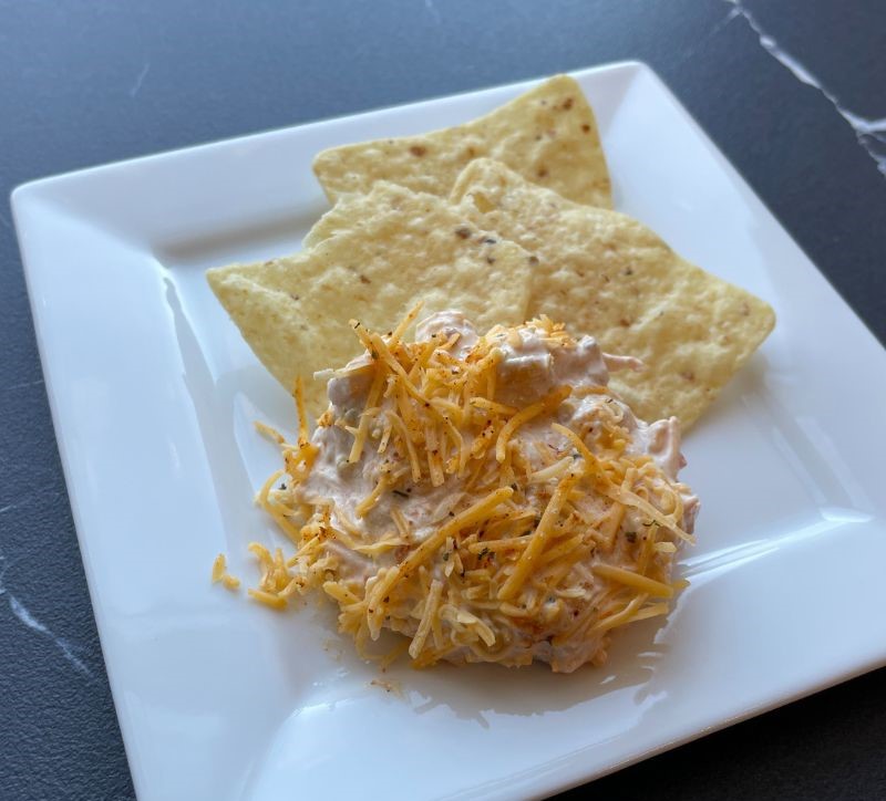 white square plate with cheese dip and tortilla chips on it