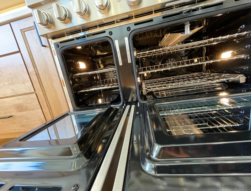 large double oven commercial range with both oven doors open showcasing oven racks and convection fans at the back
