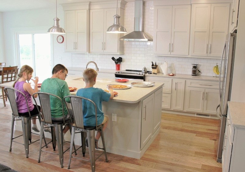 kids seated at kitchen island eating pizza