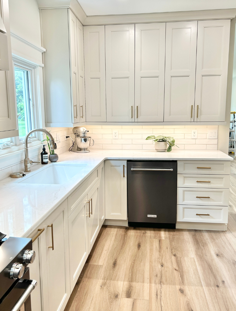 kitchen sink with window above and black stainless stee; dishwasher in corner