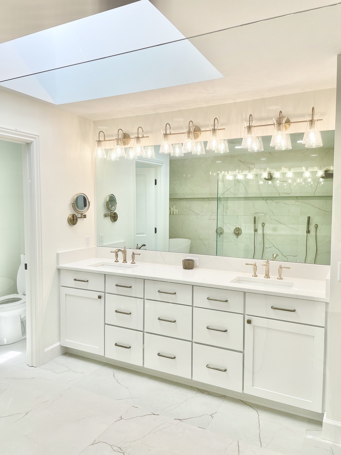 double sink vanity with white cabinetry and lots of drawers at center with large mirror and vanity lights