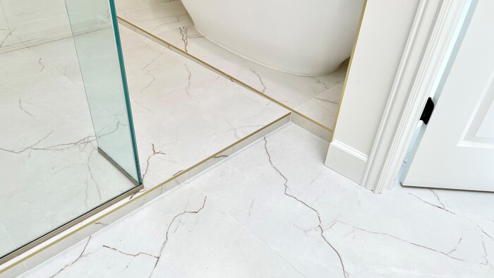 gold brass finish tile edge trim on entrance to wet room shower and tub space