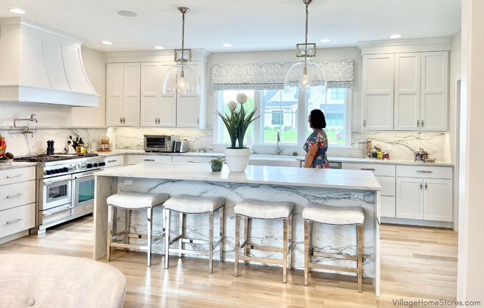 village home stores white cabinet kitchen with white quartzite countertops and light wood flooring.