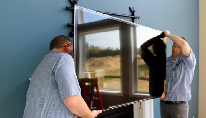 Two men install a large flat screen TV