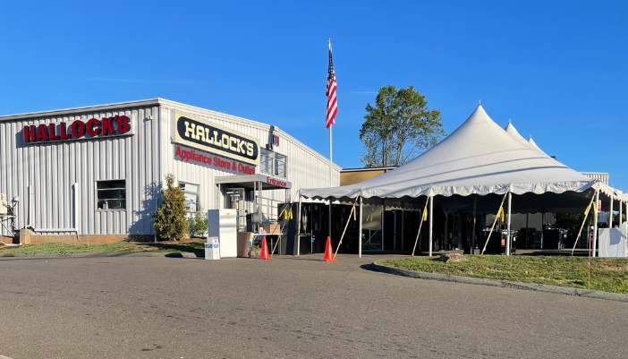 An exterior shot of Hallock's Appliances and a tent sale.