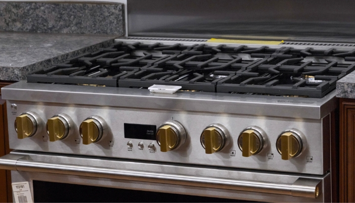 A front view of a gas range with gold knobs.