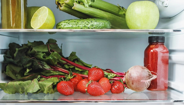 A shelf of a refrigerator with fruits and veggies visible. 