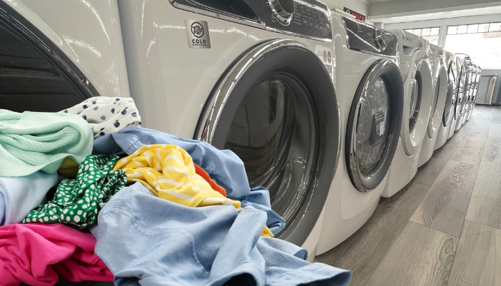 A row of washing machines with a basket of clothes in front.