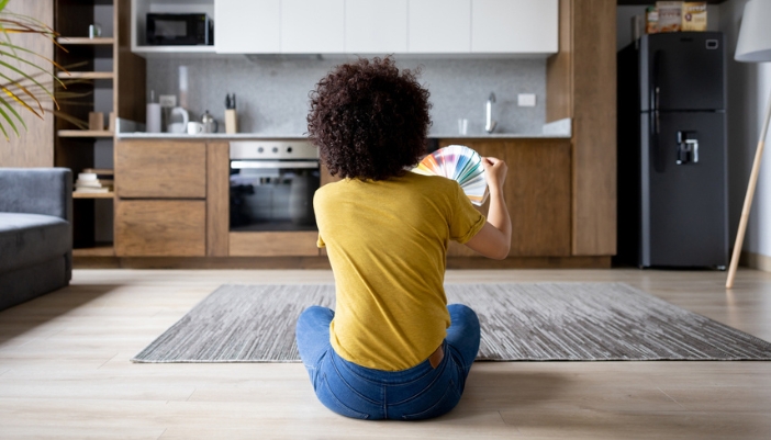 A woman flips through a color palette booklet while looking at her kitchen.