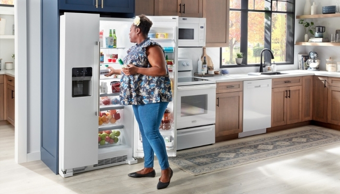 An image of a woman looking through her side-by-side refrigerator.
