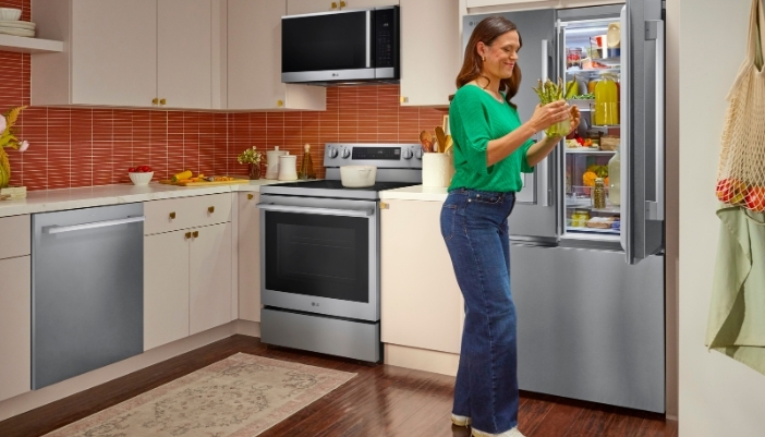 A woman pulls veggies out of her French-door refrigerator.