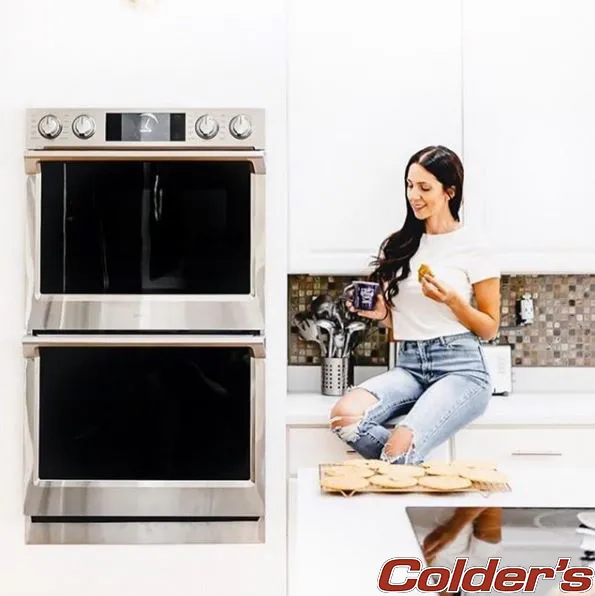 A woman sits next to her double wall oven