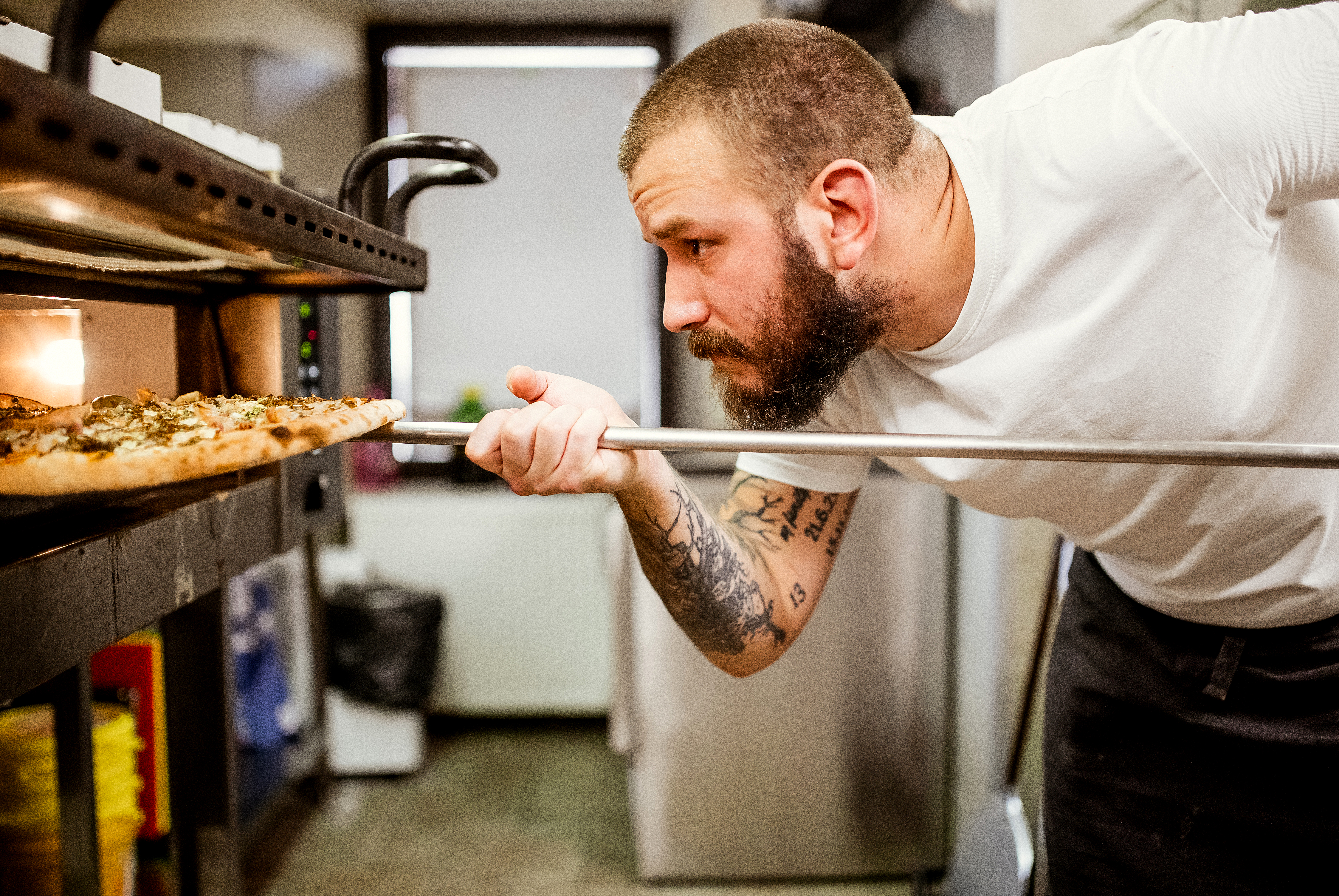 A man putting a pizza into a stone pizza oven 
