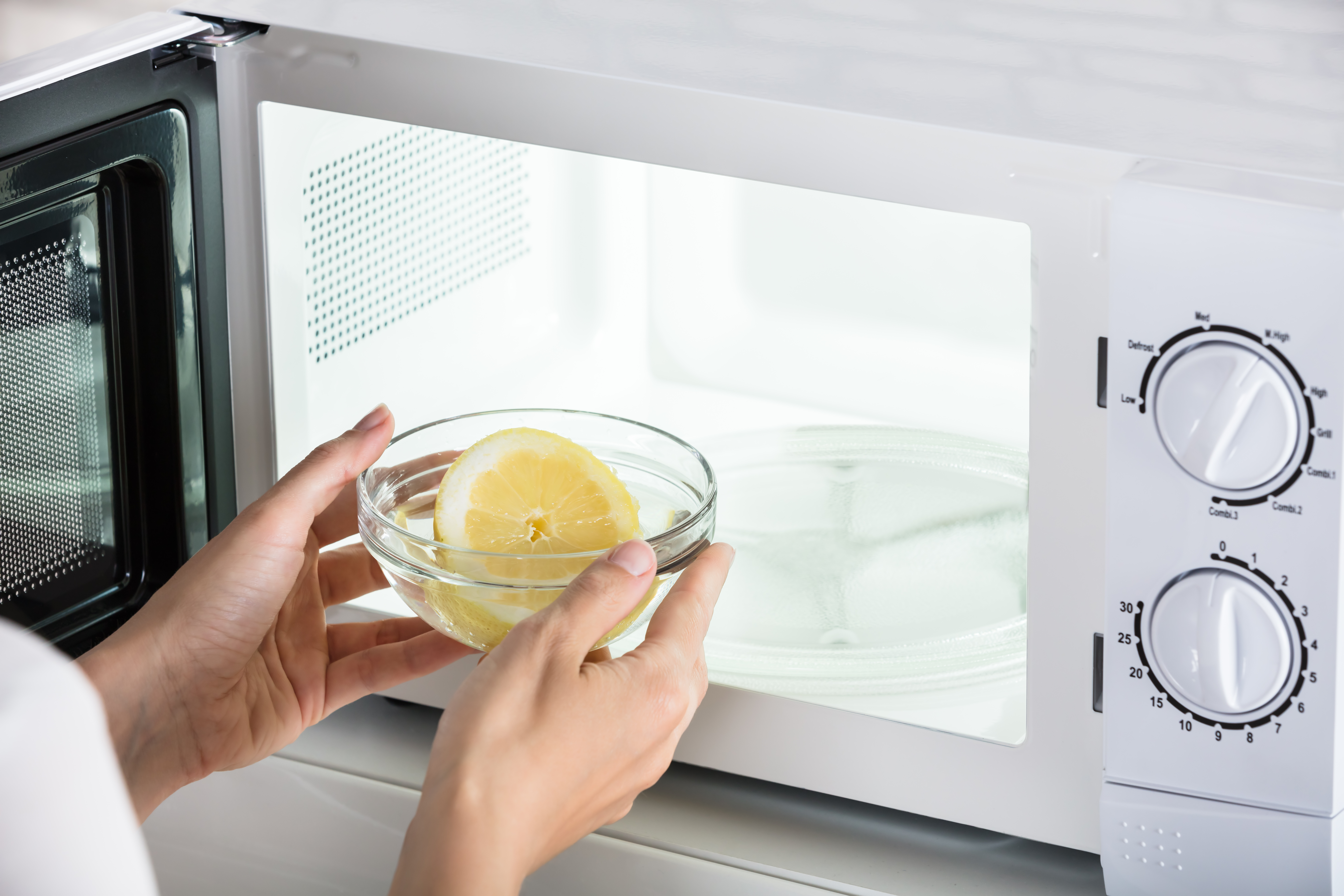 Person putting a bowl with water and lemon into a microwave