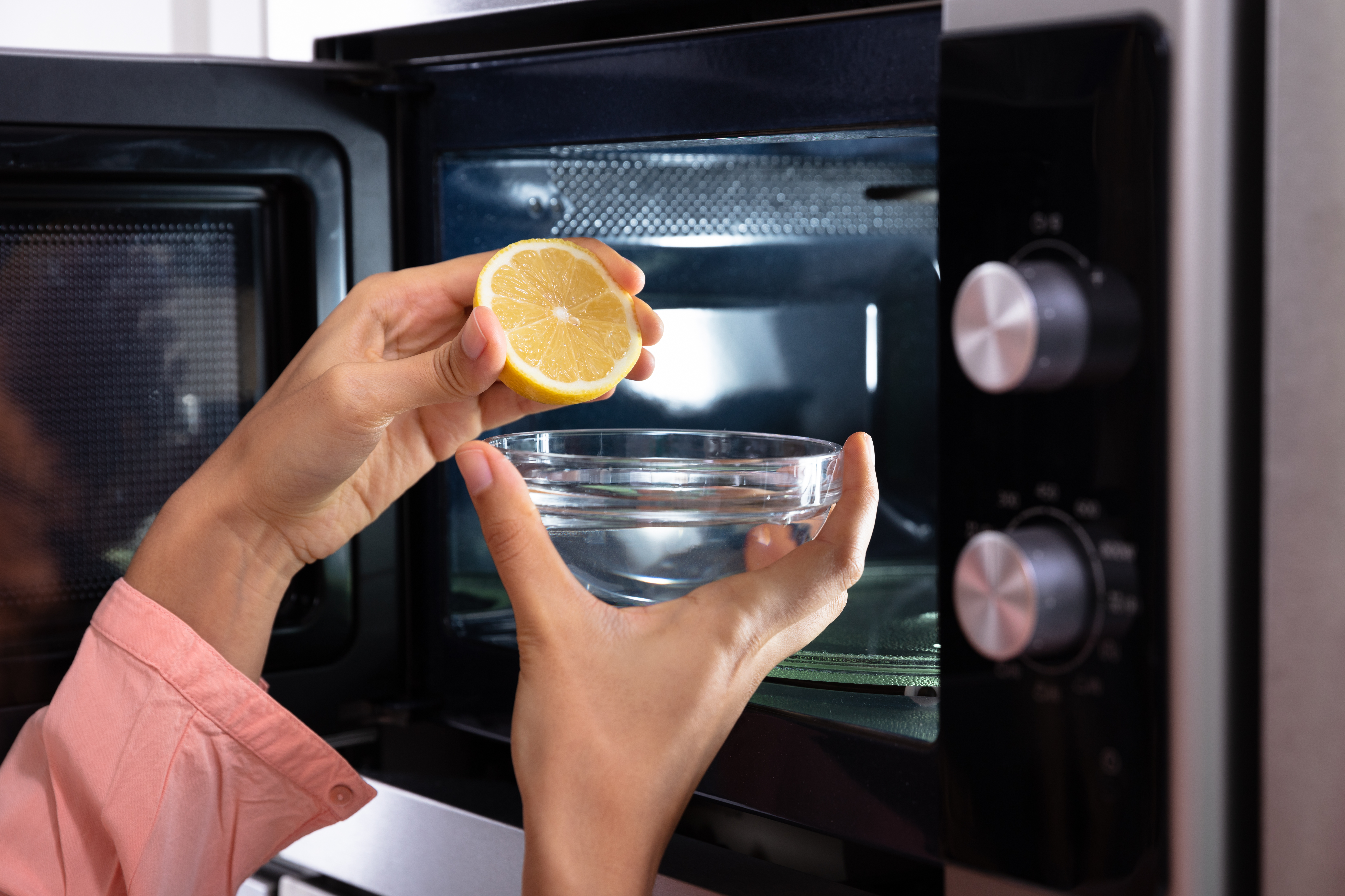 Person squeezing lemon into a bowl before placing it in a microwave 