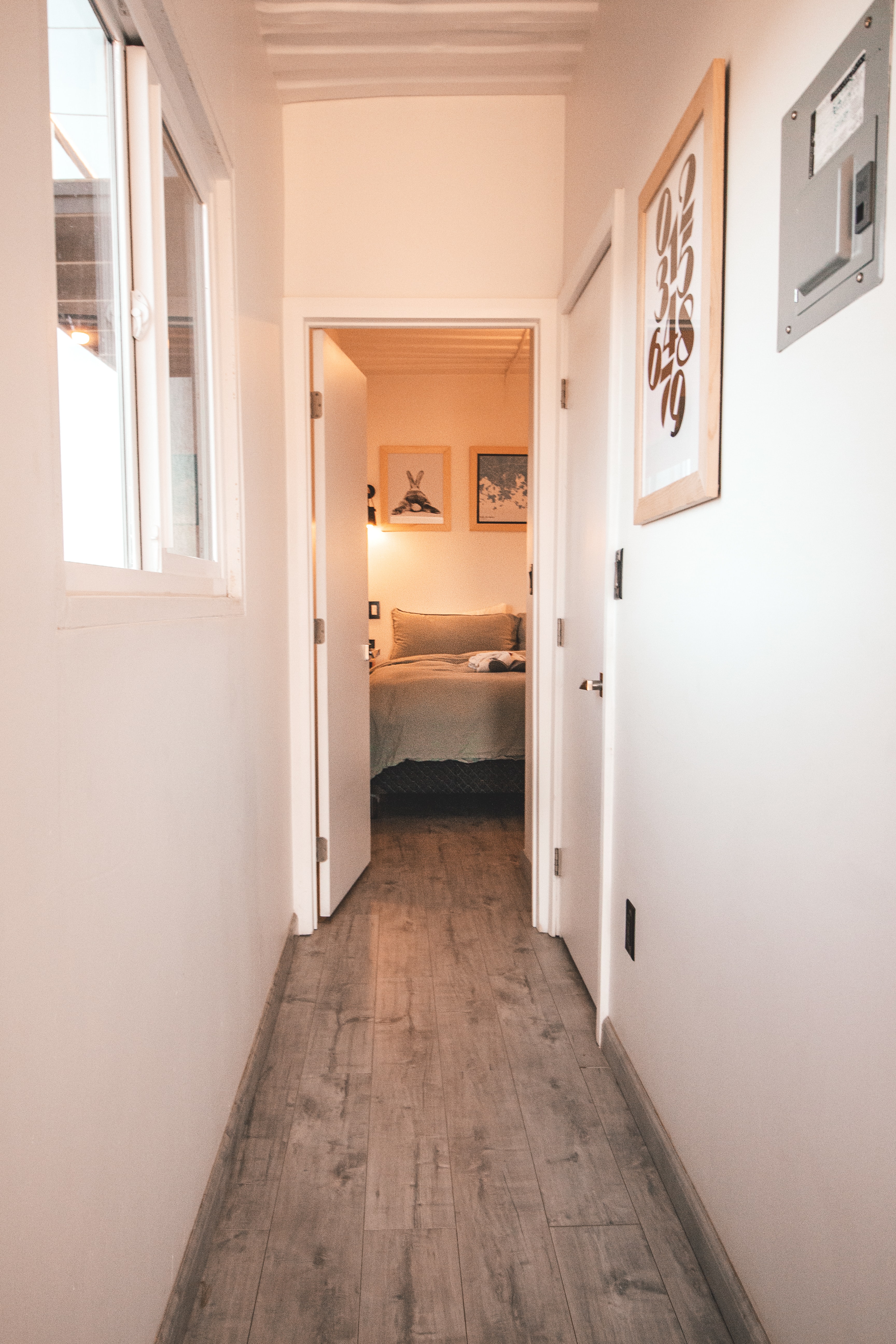 A hallway leading into a bedroom with distressed laminate flooring