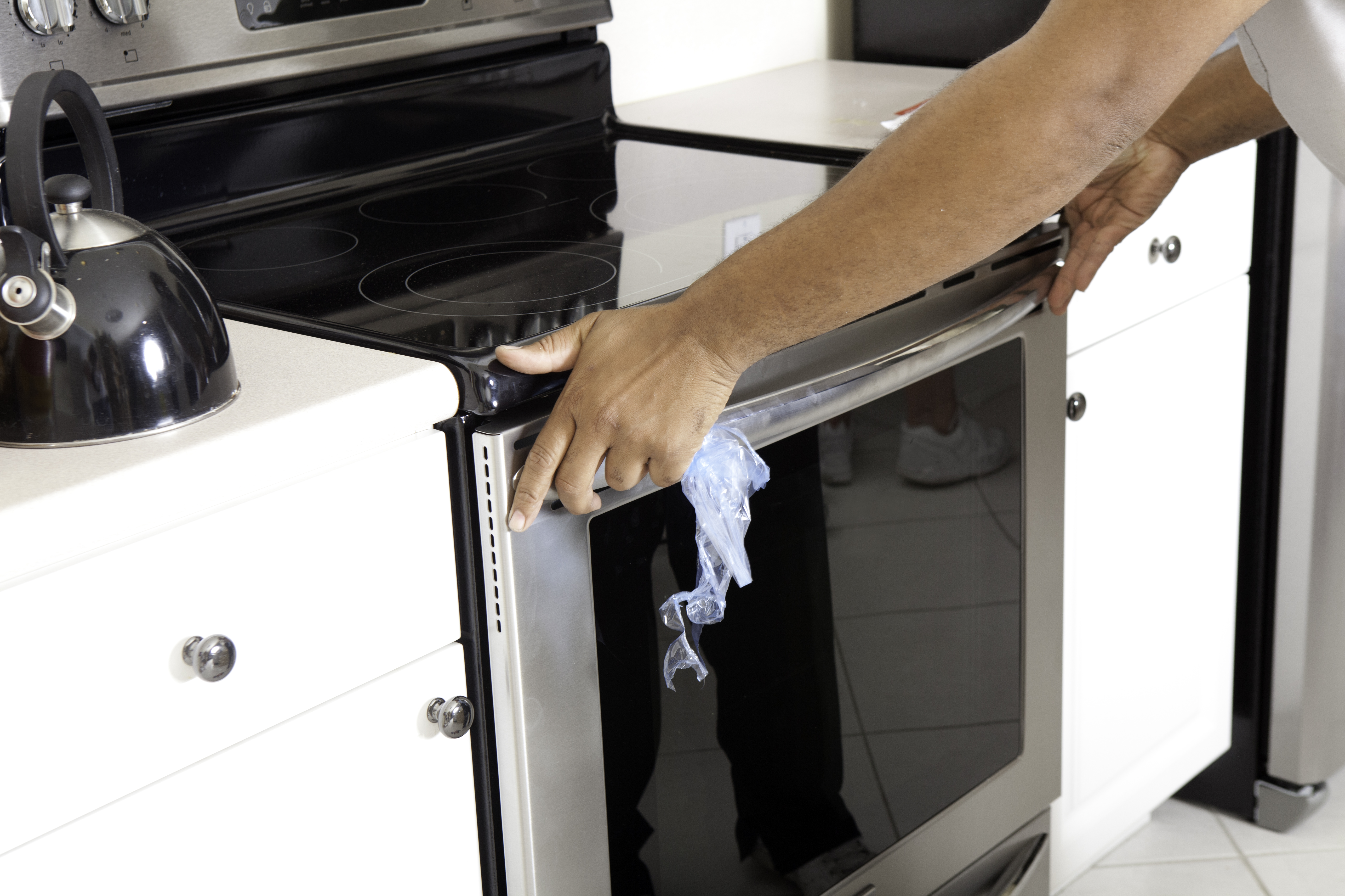 An appliance installer pushing in a slide-in ceramic top range