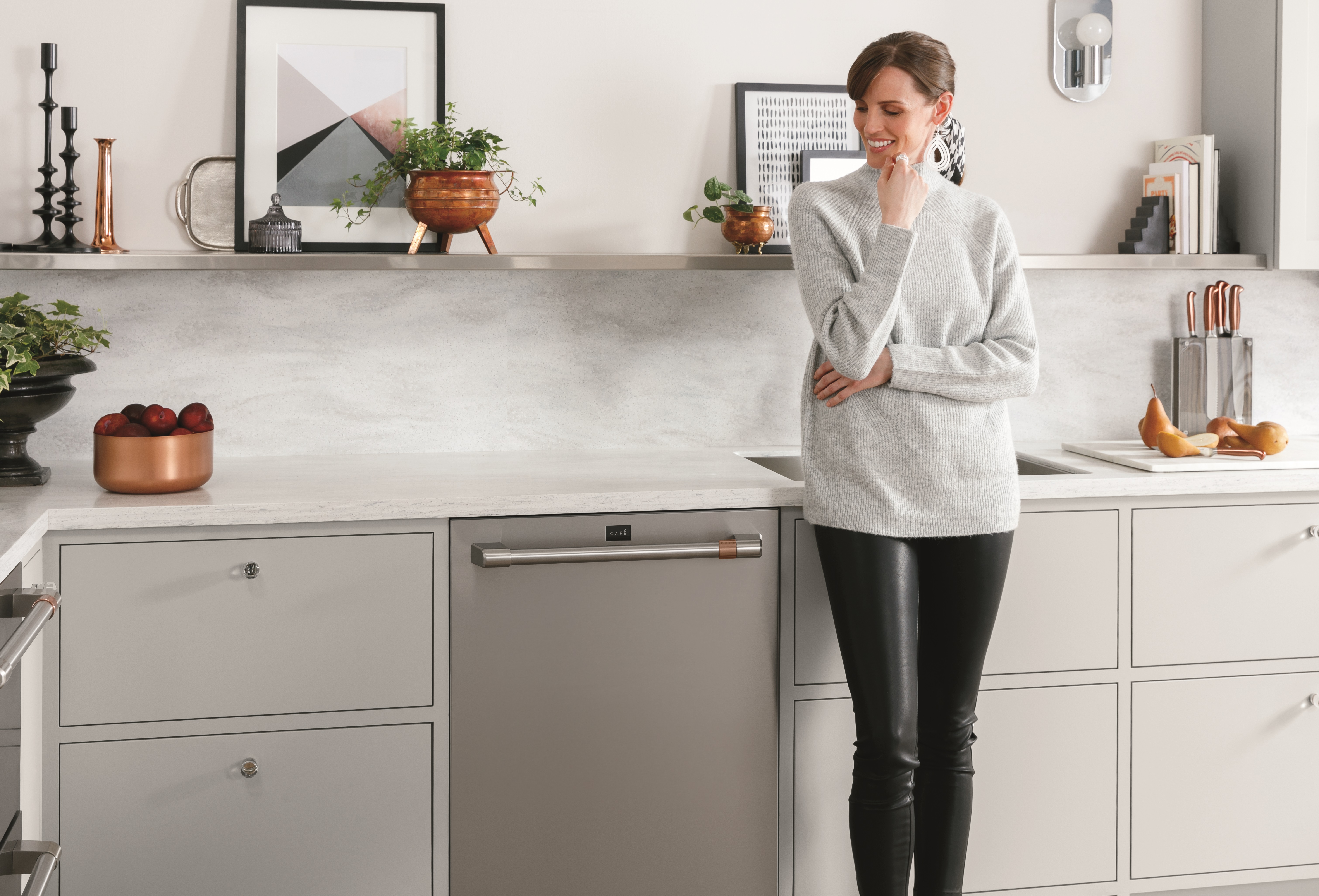 woman in casual wear stands next to cafe dishwasher and smiles 