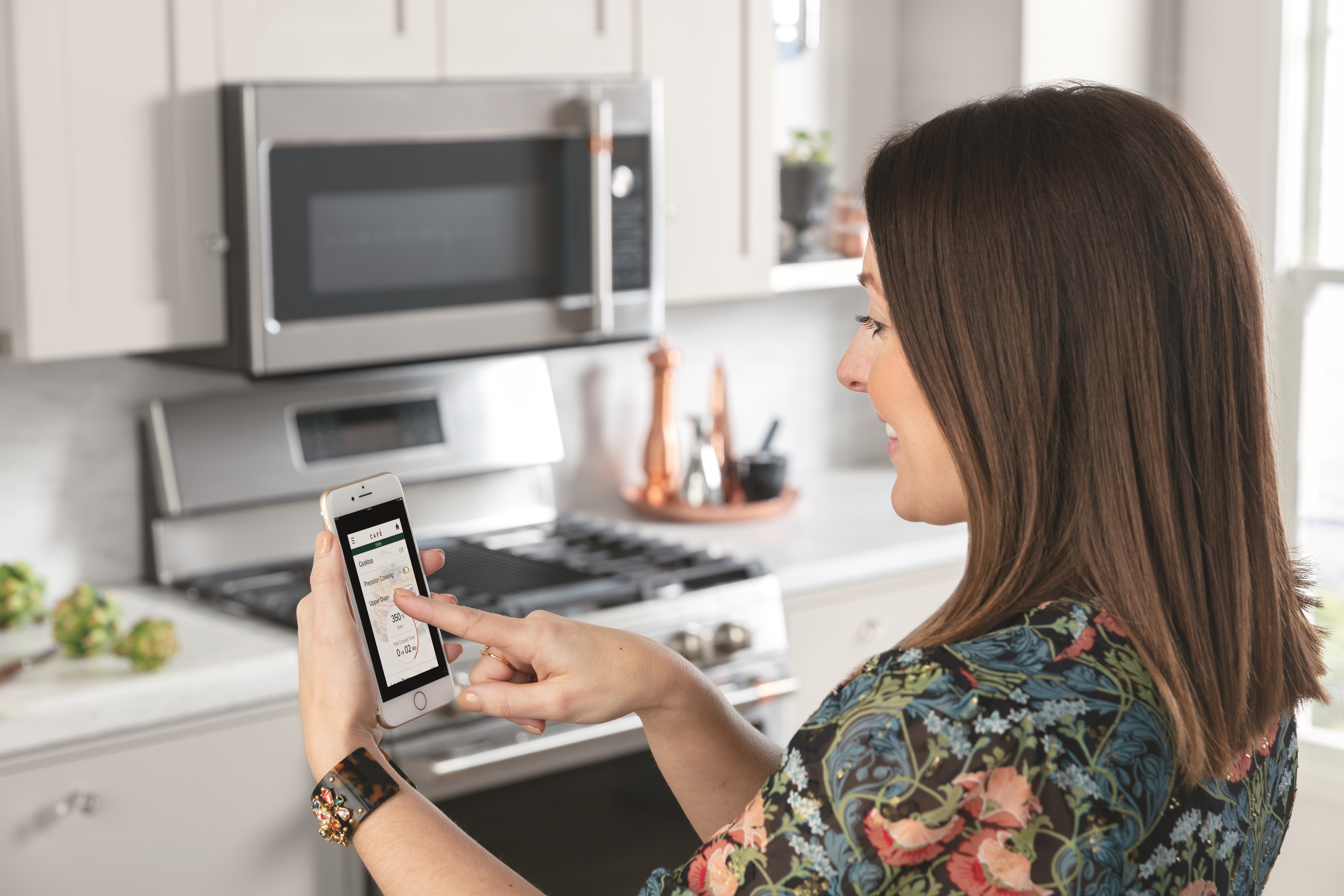 woman uses smart device to remotely program cafe microwave