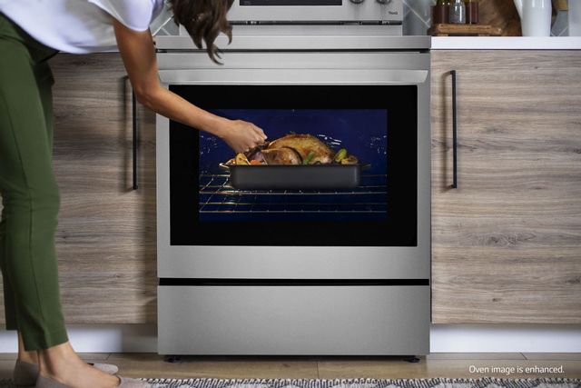 Woman standing in front of oven checking on food. 