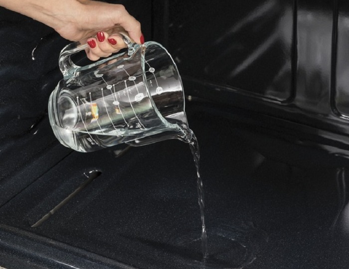 User pouring water to use steam function on GE jgss66selss range oven 