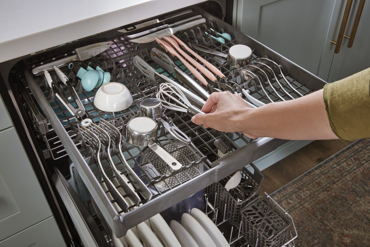 User loading cooking utensils in Whirlpool WDT750SAKZ dishwasher third rack