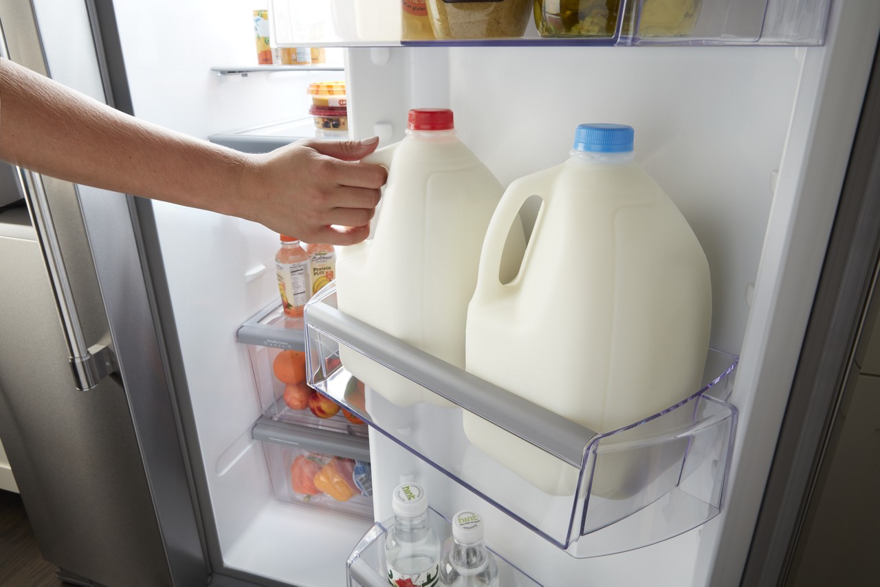 person reaching for milk from whirlpool adjustable gallon door bins