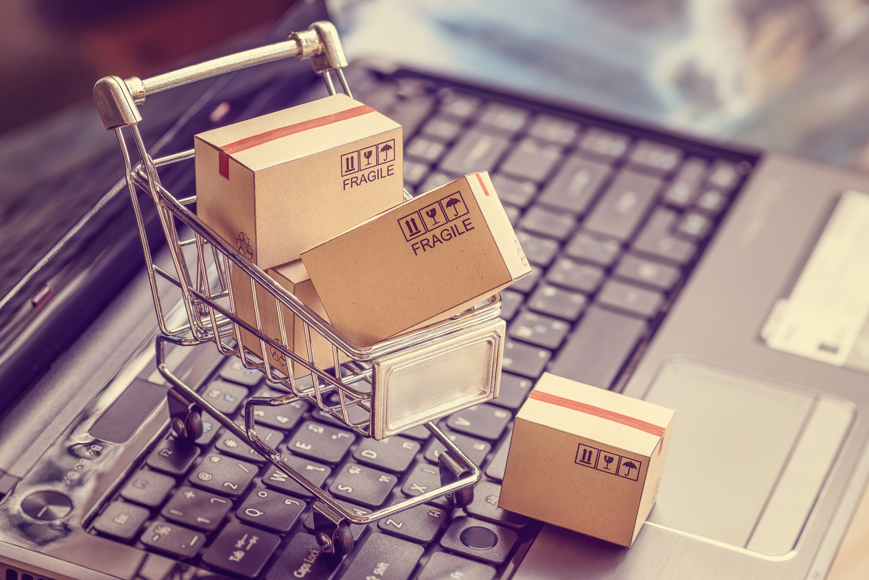 graphic of mini shopping cart full of packaging boxes on top of laptop