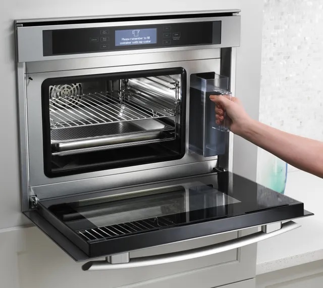 Shot of JennAir steam oven open and person grabbing water reservoir