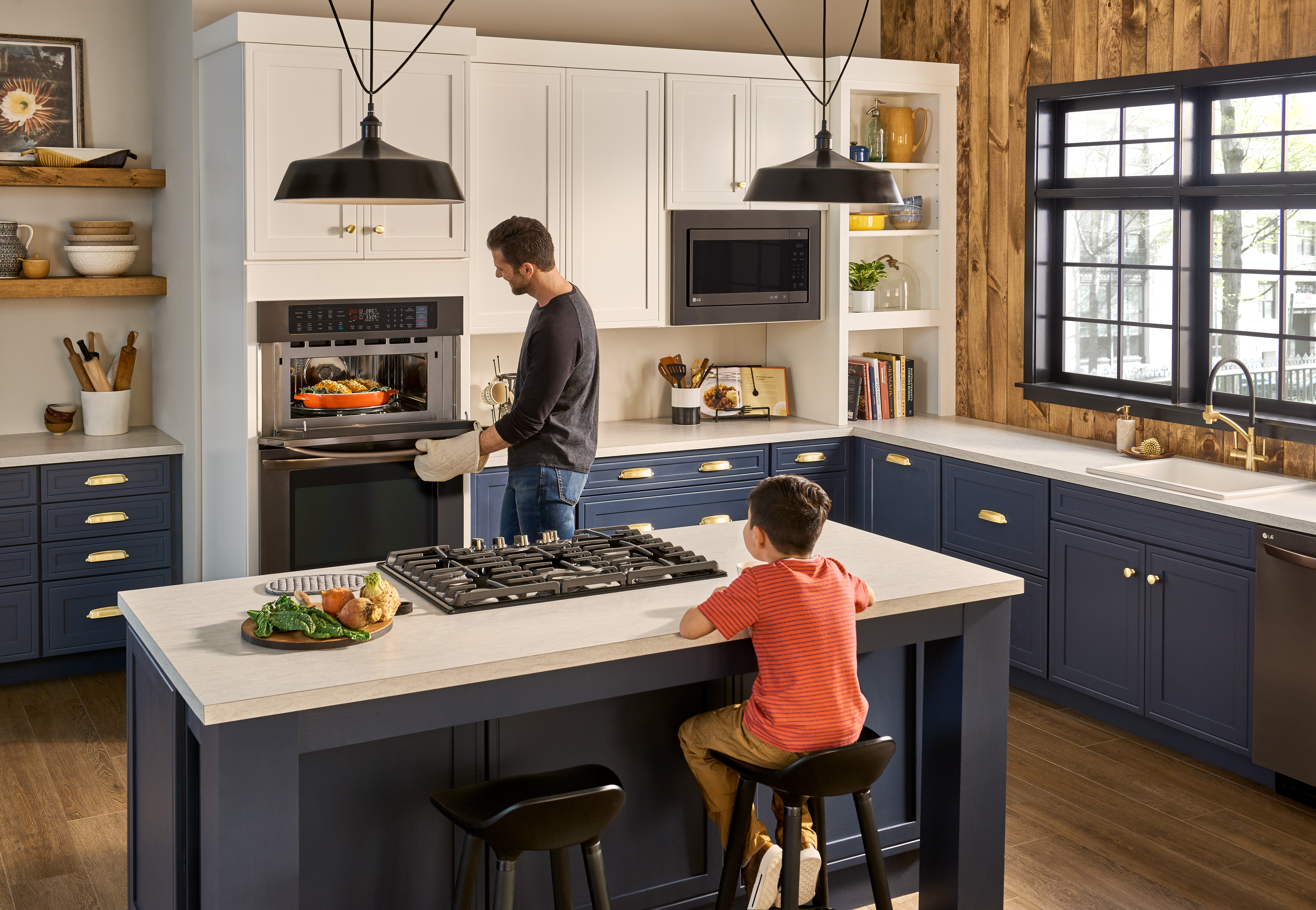 Child sits while man cooks on a LG cooktop