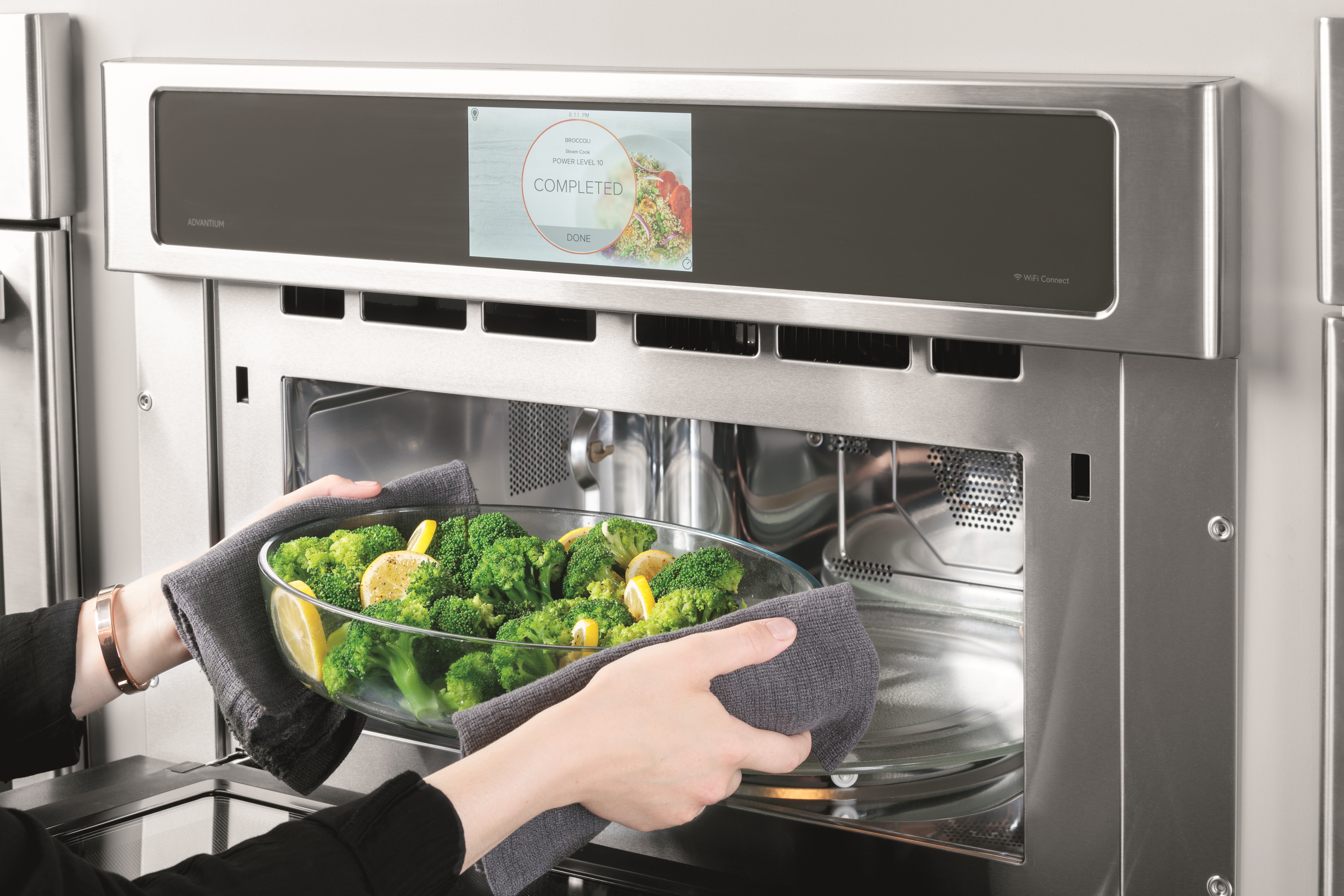 woman inserts bowl of broccoli into monogram advantium oven 