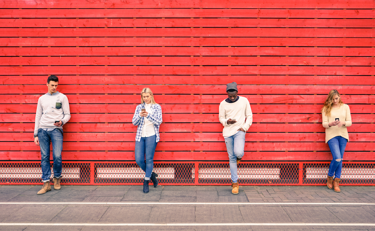 group of young adults socially distant against a red wall