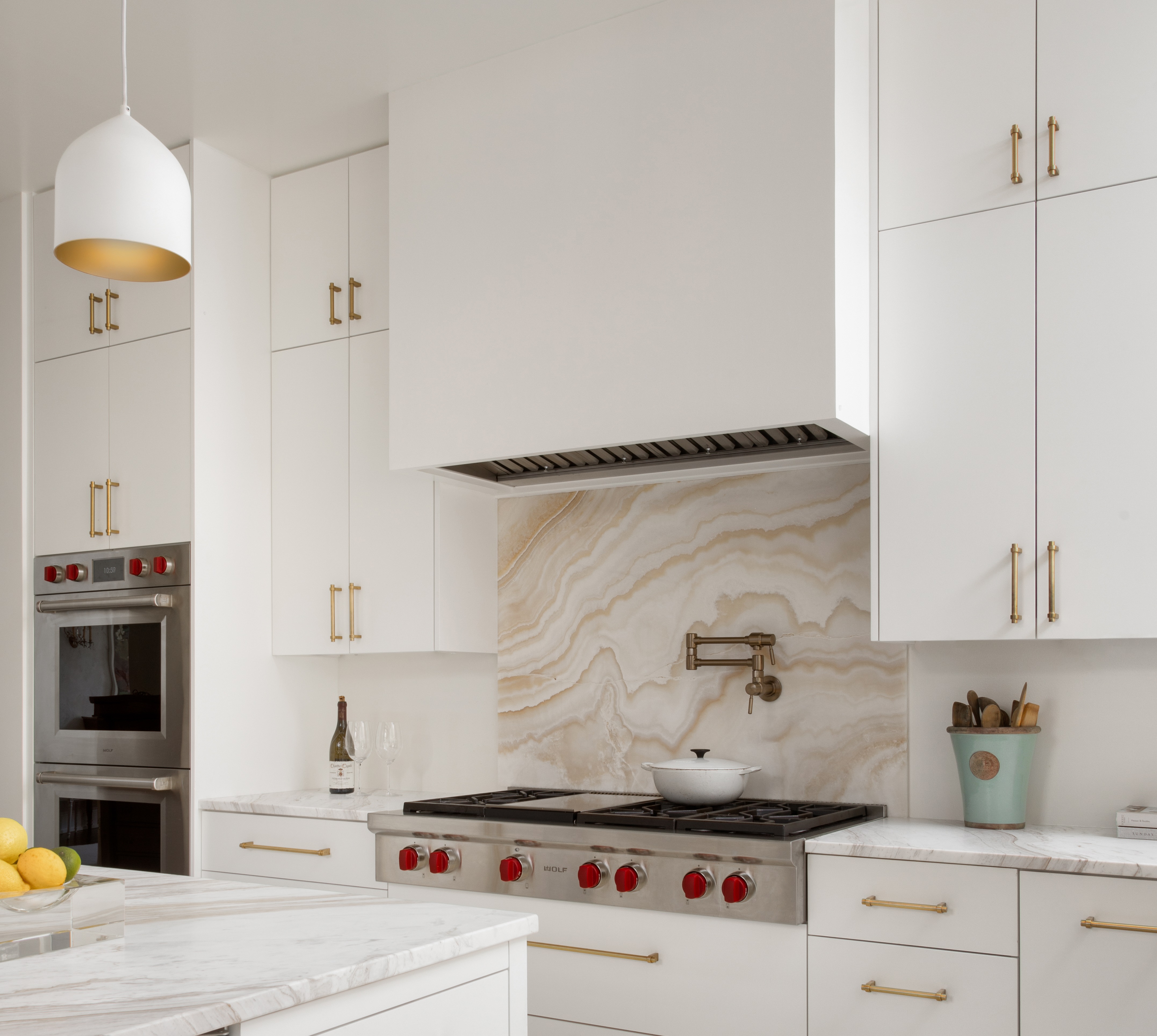 Wolf range installed with a marble backsplash and custom range hood