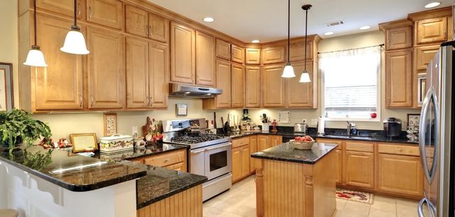 front view of a transitional kitchen with light wood cabinets and stainless steel appliances