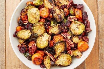 top view of a white bowl full of roasted veggies including carrots, brussel sprouts, and parsnips